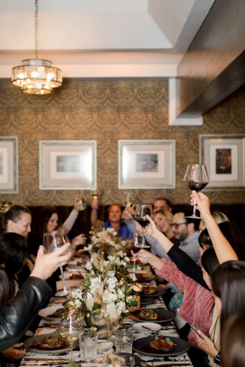 A photo of guests celebrating with wine around a dinner table