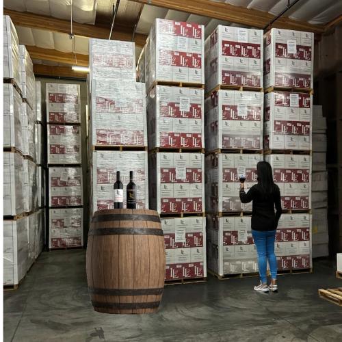 Woman standing in front of case of wine - Wine Pull warehouse wine sale