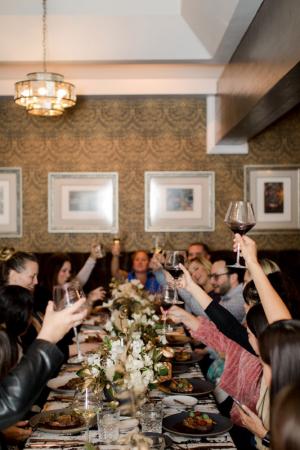 A photo of guests celebrating with wine around a dinner table